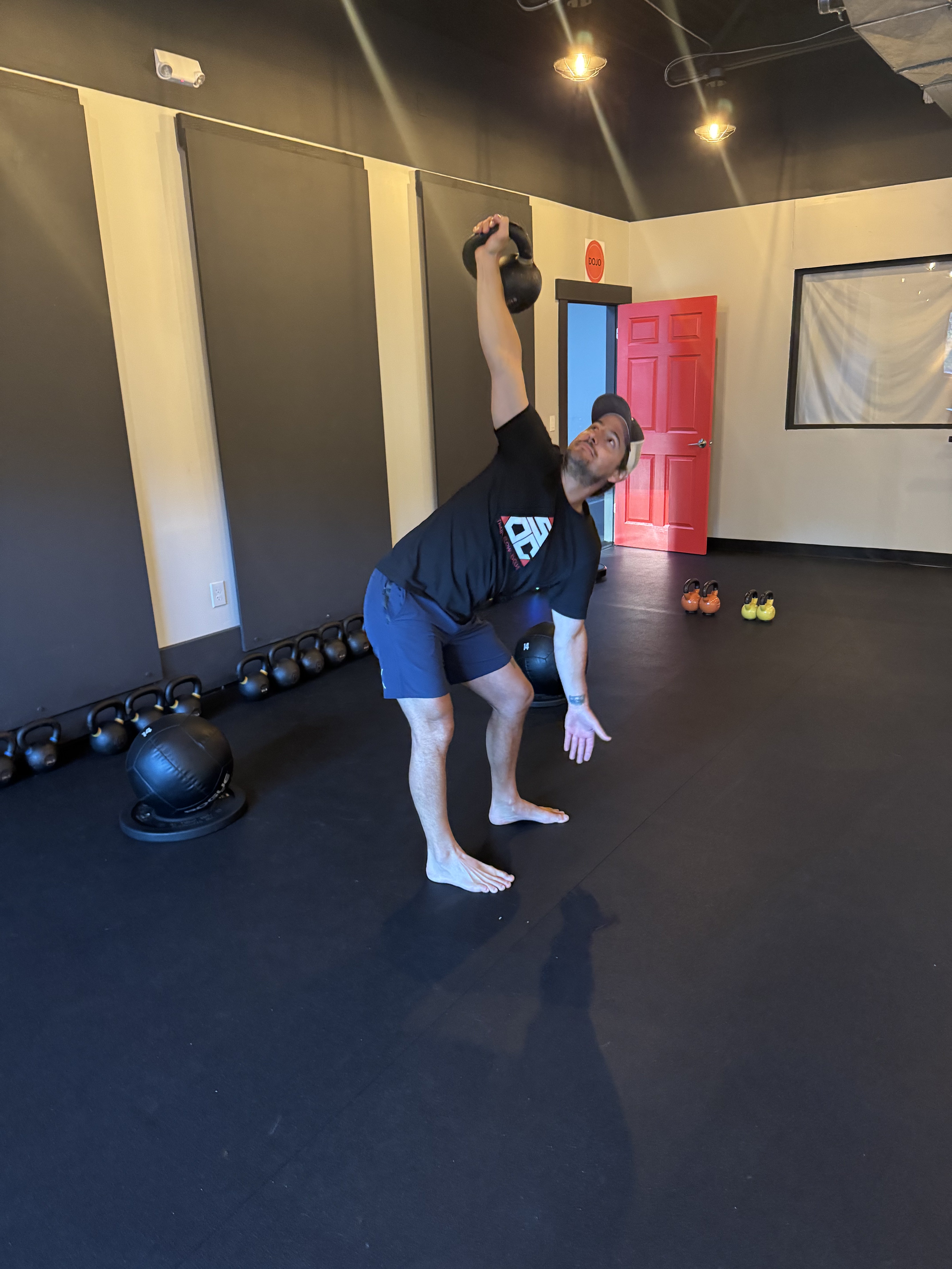 Charlie McGwire pressing a kettlebell overhead in the Strong on Center studio.