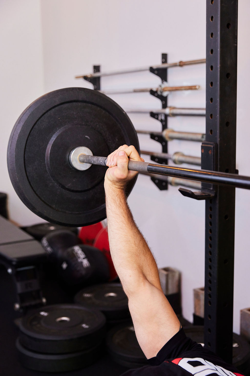 Athlete pressing a loaded barbell overhead in the Strong on Center weight room.